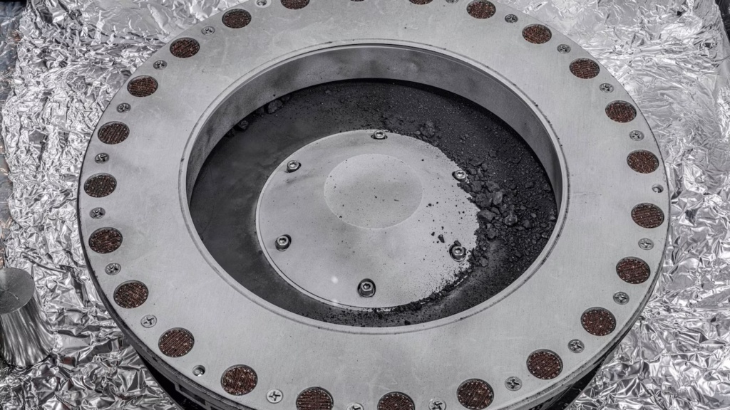 This photo provided by NASA on Wednesday, Oct. 11, 2023 shows the outside of the Osiris-Rex sample collector with material from asteroid Bennu at middle right. Scientists have found evidence of both carbon and water in initial analysis of this material. The bulk of the sample is lo(
Source: Erika Blumenfeld, Joseph Aebersold/NASA via AP